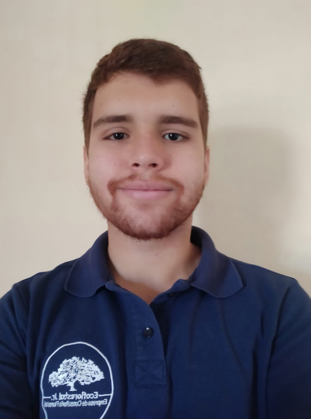 Descrição da imagem do Gabriel: olhos escuros, cabelo e barba ruiva, pele clara, está usando uma camisa polo azul, está com um leve sorriso no rosto